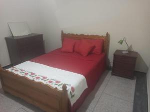 Schlafzimmer mit einem Bett mit roter Bettwäsche und roten Kissen in der Unterkunft Quartier Anne Marie in Temara