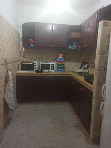 a kitchen with brown cabinets and two microwaves at Quartier Anne Marie in Temara