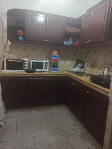 a kitchen with brown cabinets and two microwaves at Quartier Anne Marie in Temara +19 photos