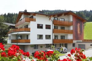 a apartment building with balconies and red flowers at Aparthotel Rubinius in Wagrain