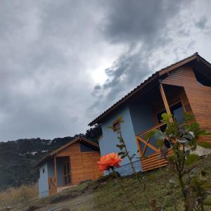 a house on a hill with a flower in front of it at Cabanas Sol Poente in Bom Jardim da Serra