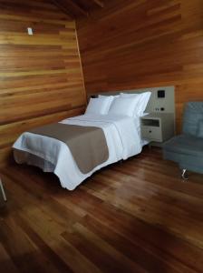 a bedroom with a large white bed and a chair at Cabanas Sol Poente in Bom Jardim da Serra
