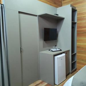 a room with a refrigerator and a television at Cabanas Sol Poente in Bom Jardim da Serra