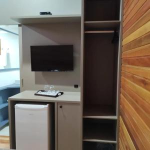 a room with a desk with a tv and a closet at Cabanas Sol Poente in Bom Jardim da Serra