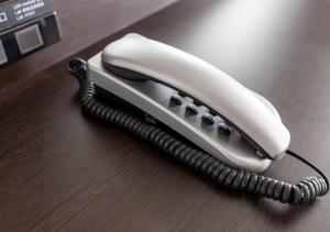 a white phone sitting on a wooden table at APA Hotel Asakusa Shin Okachimachi Ekimae in Tokyo
