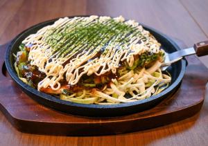 a pan of pasta with sauce and greens on a table at APA Hotel Asakusa Shin Okachimachi Ekimae in Tokyo