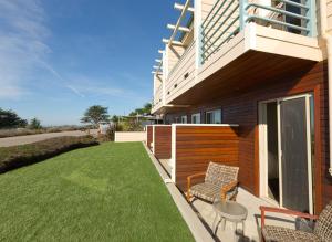 ein Haus mit einer Terrasse mit Stühlen und einer Liegewiese in der Unterkunft Cambria Landing Inn and Suites in Cambria