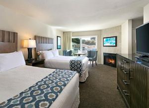 a hotel room with two beds and a fireplace at Cambria Landing Inn and Suites in Cambria