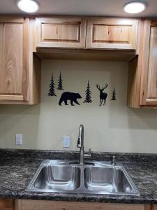 um lavatório de cozinha com veado e um urso na parede em Nunaka Valley Cottage em Anchorage