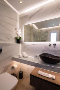 een badkamer met een wastafel, een toilet en een spiegel bij Aronia Luxury Apartments Karpathos in Karpathos
