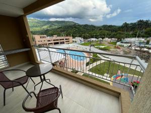 einen Balkon mit Stühlen und Poolblick in der Unterkunft Apartamento con piscina y parqueadero a 7 min del centro in Villeta