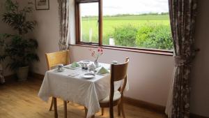 a table with a white table cloth on it with a window at Greenfields Farmhouse in Ballylongford