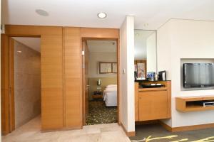 a hotel room with a television and a bedroom at Crowne Plaza Zhongshan Wing On City, an IHG Hotel in Zhongshan