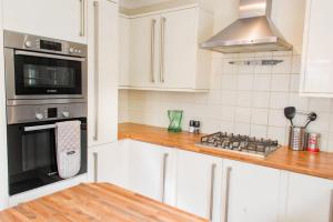 a kitchen with white cabinets and a stove top oven at Host & Stay - Laylands Yard in Wells next the Sea +18 photos