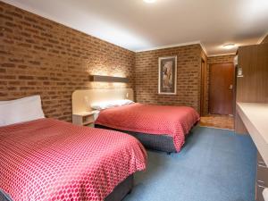 Habitación de hotel con 2 camas y pared de ladrillo en Eildon Parkview Motor Inn Room 3, en Eildon