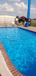 a large blue swimming pool with chairs and a table at Motel 6-Lawton, OK in Lawton