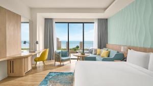 a hotel room with a bed and a desk and chairs at Holiday Inn Resort Ho Tram Beach by IHG in Ho Tram