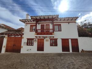 a white house with wooden doors and a balcony at Merak Hostel in Villa de Leyva