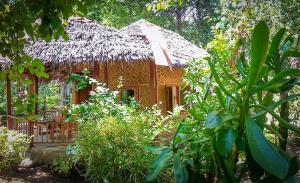 una pequeña casa de madera con techo de paja en Sunset Cottages, en Hitokalak