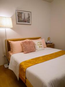1 dormitorio con 1 cama grande con almohadas rosas y amarillas en LFCM Condo Home @ Mesatierra Residences Davao City en Davao
