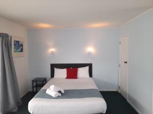 a bedroom with a large white bed with red pillows at Marlin Court Motel in Paihia