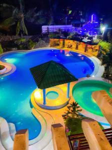 uma grande piscina à noite com um guarda-chuva em Jazkimronan Resort em Talisay