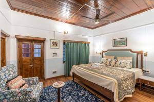 Un dormitorio con una cama, un sofá y una silla. en StayVista at Vintage Musings 3BR in Dharamshala with vintage charm, en Dharamshala