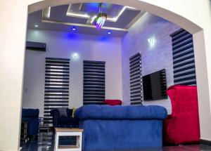 a living room with a blue couch and red chairs at Prince's - Villa - Minimum of 3 nights booking in Akure