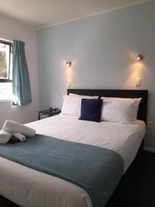 een slaapkamer met een groot bed en een blauwe deken bij Marlin Court Motel in Paihia