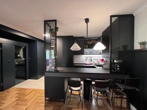 a kitchen with black cabinets and a bar with stools at Apartment Przno in Sveti Stefan