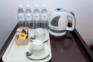 een koffiezetapparaat en kopjes op een dienblad met flessen water bij D&F BOUTIQUE HOTEL SENAWANG in Senawang
