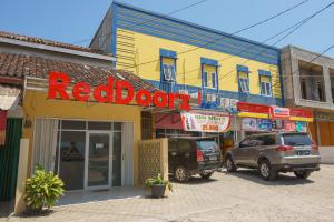 un negozio di porte rosse con macchine parcheggiate di fronte di RedDoorz near Kampus UIN Lampung a Tanjungkarang