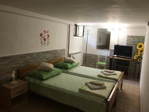 een slaapkamer met een bed met groene lakens en een televisie bij Apartmani Luiza in Cres