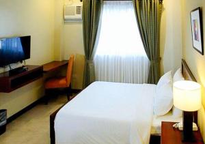 um quarto com uma cama branca e uma janela em RedDoorz Plus @ Conclave Hotel Davao City em Davao