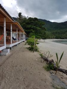 a beach with a building and a beach with trees at Bottle Beach 2 Bungalows in Bottle Beach