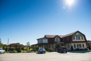 a large building with cars parked in a parking lot at Conacul de pe Lac in Şagu