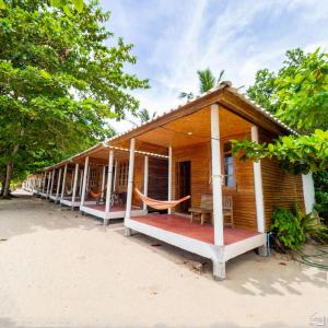 a wooden house with a porch on a beach at Bottle Beach 2 Bungalows in Bottle Beach