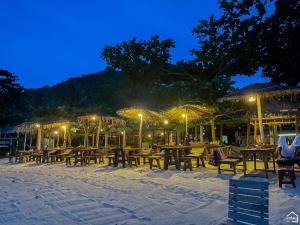 a group of tables and chairs on the beach at night at Bottle Beach 2 Bungalows in Bottle Beach