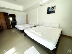 two beds in a room with white sheets at Bottle Beach 2 Bungalows in Bottle Beach