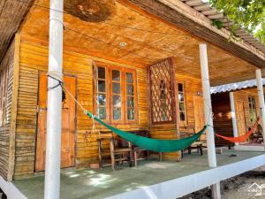 a hammock on the porch of a wooden house at Bottle Beach 2 Bungalows in Bottle Beach