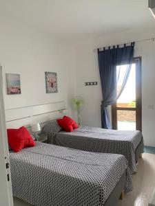 two beds with red pillows in a room at Casa Capo Falcone - Terraced house with wonderful sea view - in Stintino