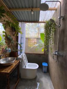 a bathroom with a toilet and a sink and a window at La Maison Homestay Măng Đen in Kon Tum +54 photos