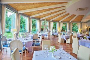 a restaurant with white tables and chairs and windows at Skandinavia Country Club and SPA in Sestroretsk