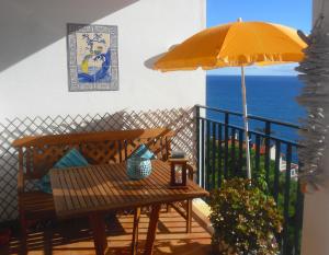 a patio with a bench and an umbrella and the ocean at Apartment Palma Madeira wandern und tauchen in Caniço