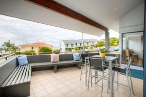 uma varanda com um banco, uma mesa e cadeiras em Coffs Jetty Beach House em Coffs Harbour