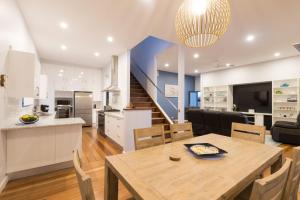 a kitchen and living room with a wooden table and a dining room at Coffs Jetty Beach House in Coffs Harbour
