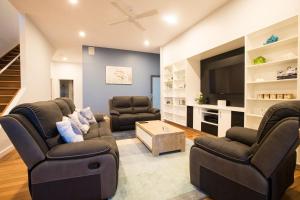 uma sala de estar com 2 sofás e uma televisão de ecrã plano em Coffs Jetty Beach House em Coffs Harbour