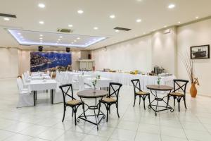 a banquet hall with white tables and chairs at Opera House Hotel in Symi