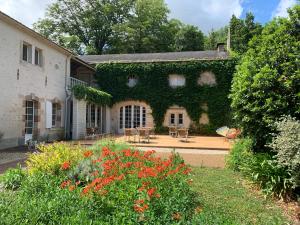 um edifício coberto de hera com mesas e cadeiras num jardim em Clos de la Court d'Aron em Saint-Cyr-en-Talmondais