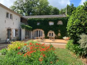 an ivycovered building with tables and chairs in a garden at Clos de la Court d'Aron in Saint-Cyr-en-Talmondais